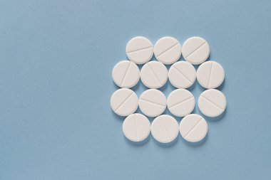 Mavi masaya saçılmış beyaz haplar. Reklam, web geçmişi ya da diğer fikirler için özel teklifler alın. Tıbbi, eczane ve sağlık hizmetleri konsepti. Uzayı kopyala Metin veya logo için boş yer