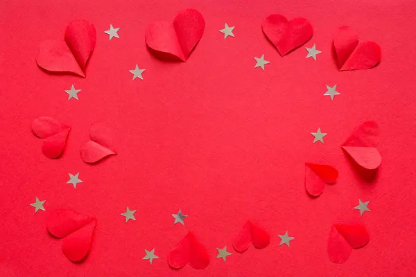 Valentine\'s, birthday or wedding day festive pattern, many red paper hearts and confetti stars for greeting card on red background top view and flat lay.
