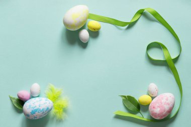 Paskalya yumurtası ve dekoratif kurdeleli Paskalya konsepti! Kopyalama alanı olan hassas pastel mavi arkaplan. Düz yatıyordu