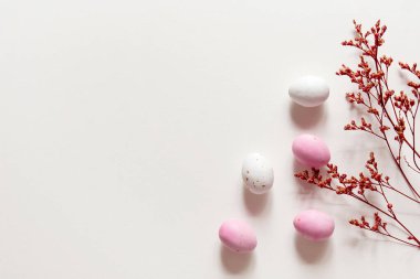 Paskalya minimalist kavramı, pembe ve beyaz paskalya yumurtaları ve bir buket kuru çiçek. Kopyalama alanı olan pastel boş arkaplan.