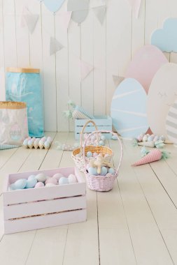 Paskalya içleri. Renkli yumurtalarla dolu sepet ve kutu. Paskalya arkaplanı, beyaz ahşap zeminde yumurta ve havuç.