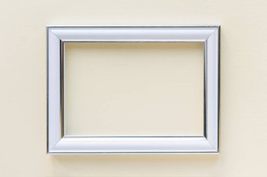 En az boş dikdörtgen beyaz çerçeve resmi açık bej duvarda asılı duruyor