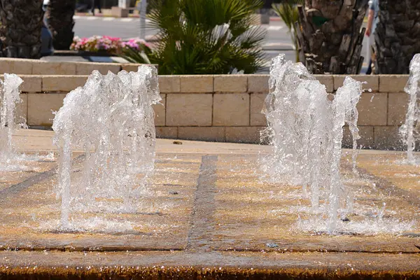 在城市的公园里泼洒泉水 成排的喷泉 免版税图库照片