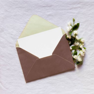 Beyaz arka planda beyaz kart, zarf ve bir buket yasemin çiçekli anneler günü pankartı.