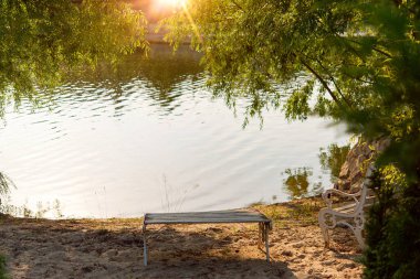 Bir yaz günü, gün batımında, göl kıyısında ahşap bir bank.