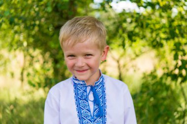 Portrait of a joyful boy in Ukrainian traditional national clothes - vyshyvanka. Ukraine, child in nature