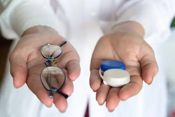 Doktor gözlük ve lens tutuyor, yakın plan. Seçim konsepti