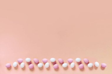 Mutlu Paskalya Bayramı dekorasyonu. Renkli şeker yumurtaları. Pembe kağıttan arka planda.