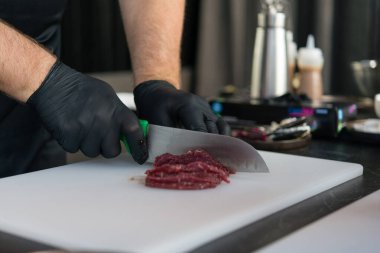 Şef et hazırlıyor, ince dilimler için çiğ et dilimleri, kıyma, sığır eti tartar.