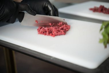 Şef et hazırlıyor, ince dilimler için çiğ et dilimleri, kıyma, sığır eti tartar.
