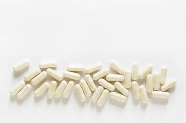 Beyaz arka plana saçılmış beyaz kapsüller. farklı haplar ve haplar, ilaç ilaçları sağlık