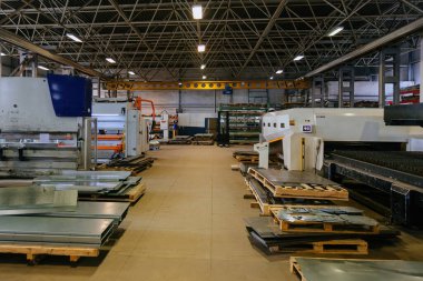 Metal fabrikası üretim hattında işçiler ve endüstriyel makineler.