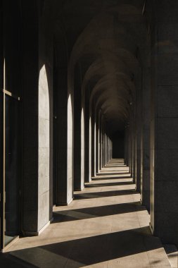 Corridor with rows of columns in sunlight.