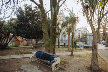 Homeless man or alcoholic sleeping on bench. Poor man on city street.