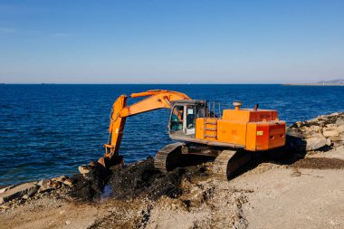 Excavator working on earthmoving at construction of new embankment.