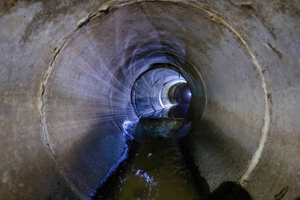 Sewage flowing inside round underground urban sewer tunnel.