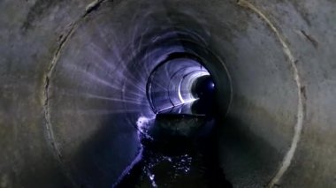 Dirty sewage flowing in round underground sewer tunnel