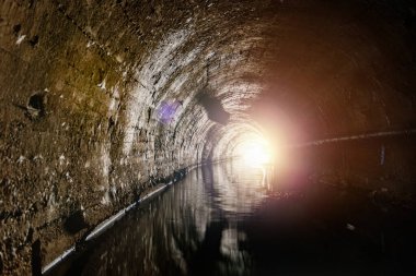 Underground vaulted urban sewer tunnel with dirty sewage.