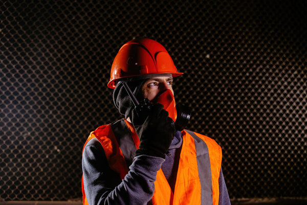 Man in respirator talking on walkie-talkie during fire in industrial building.