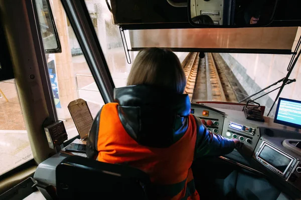 Subway train driver on workplace, view from behind.
