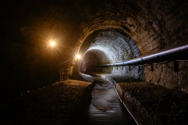 Underground vaulted urban sewer tunnel with dirty sewage.
