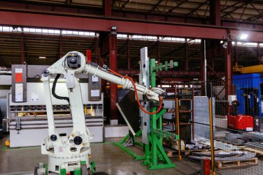 Metal fabrikasında metal levhalarla çalışan robot kol..