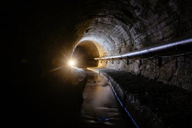 Underground vaulted urban sewer tunnel with dirty sewage.