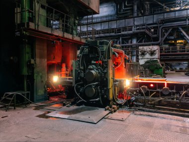 Yuvarlanan metal fabrikası. Taşıyıcılarda hareket eden sıcak çelik çubuk.
