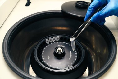 Eldivenlerdeki bilim adamları, DNA örnekleriyle test tüplerini santrifüje koydular..