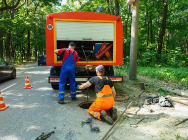 Lağım işçileri rögar kapağını temizliyor ve kanalizasyonu açıyor.