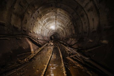 Paslı demiryolu ile terk edilmiş karanlık metro tüneli.