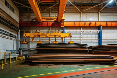 Üstünde çelik levhalar yükleyen elektromanyetik ışın tutucuları olan vinç.