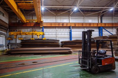 Üstünde çelik levhalar yükleyen elektromanyetik ışın tutucuları olan vinç.