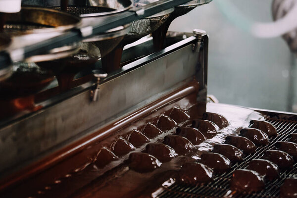 Process of chocolate glazing zephyrs in confectionery on conveyor machine. Marshmallow production line.