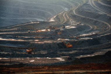 Kazı araçları ve çöp kamyonları madencilik ve işleme tesisinde açık maden ocağında yer değiştirme üzerinde çalışıyorlar..