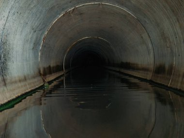 Indide dark round underground urban sewer tunnel.