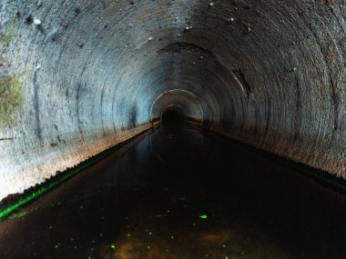 Indide dark round underground urban sewer tunnel.