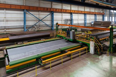 Metal işleme atölyesinde silindir konveyör üzerinde hareket eden çelik sac.