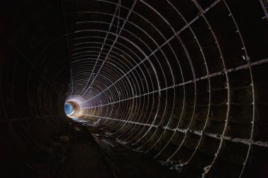 Paslı demiryolu ile terk edilmiş karanlık metro tüneli.