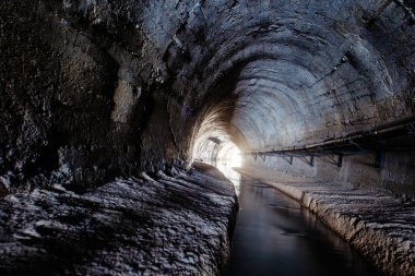 Underground vaulted urban sewer tunnel with dirty sewage.