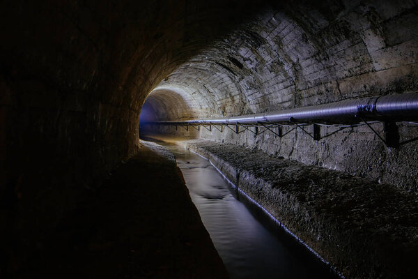 Underground vaulted urban sewer tunnel with dirty sewage.