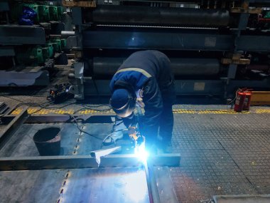 Koruyucu maske takan fabrika işçisi demir parçaları kaynaştırıyor..