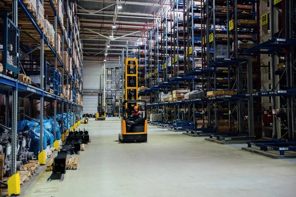 Forklift loader in Modern warehouse interior with shelves and boxes.