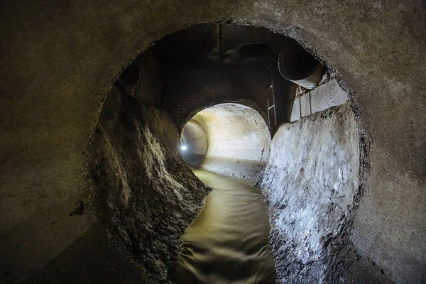 Inside underground urban sewer system. Sewage flowing in round sewer pipe.