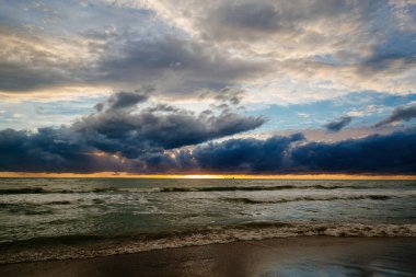 Gün batımında ya da denizde şafakta. Dramatik bulutlu gökyüzü.