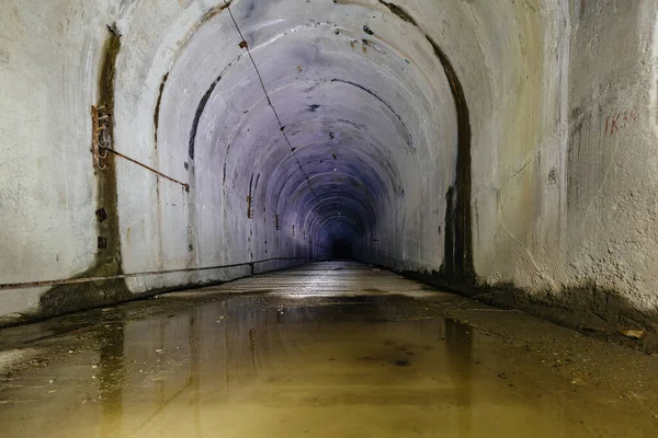 Dark flooded dirty tunnel at old underground bunker.