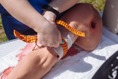 Sıhhiye silahlandırmak için turnike uygular. Tıp eğitimi.