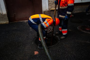 Lağım işçileri rögar kapağını temizliyor ve kanalizasyonu açıyor..