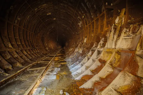 Paslı demiryolu ile terk edilmiş karanlık metro tüneli.