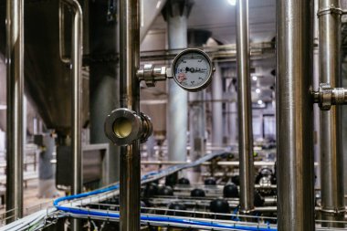 Modern bira fabrikasındaki büyük endüstriyel paslanmaz çelik borular ve basınç göstergesi..